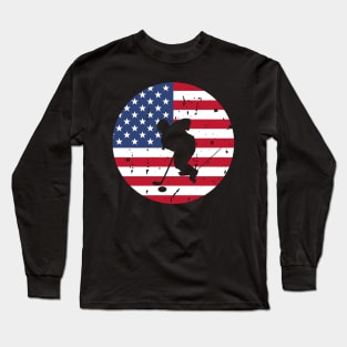 American Flag and Ice Hockey Player Silhouette, A silhouette of an ice hockey player overlaid on a distressed American flag, encapsulating patriotism and sportsmanship. Long Sleeve T-Shirt